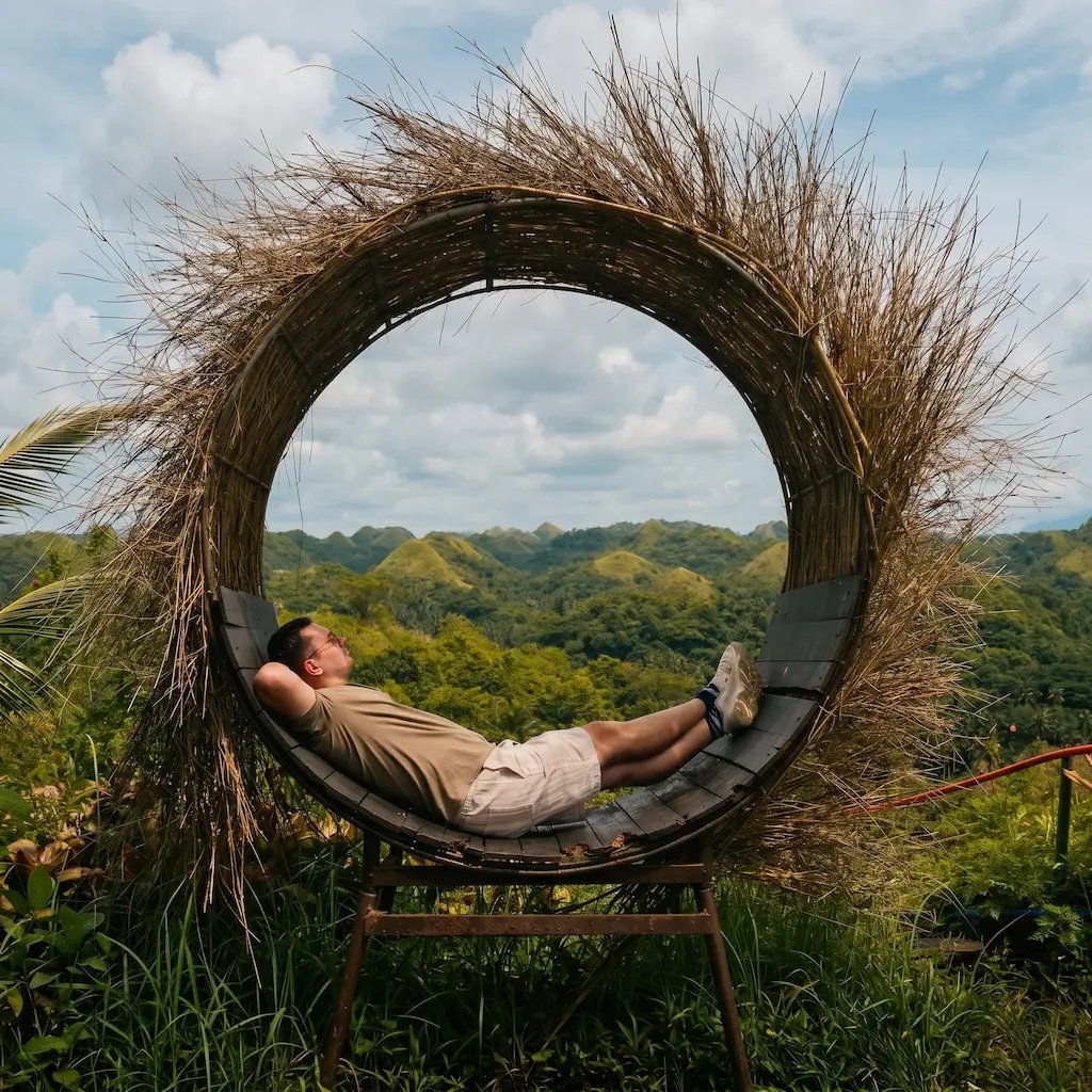 Man resting inside a large bird's nest photo spot made of dried grass
