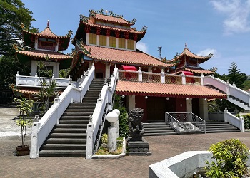 Ma Cho Temple in La Union, a vibrant Chinese-style temple with red roofs, white staircases, and statues, set against a clear sky and greenery.