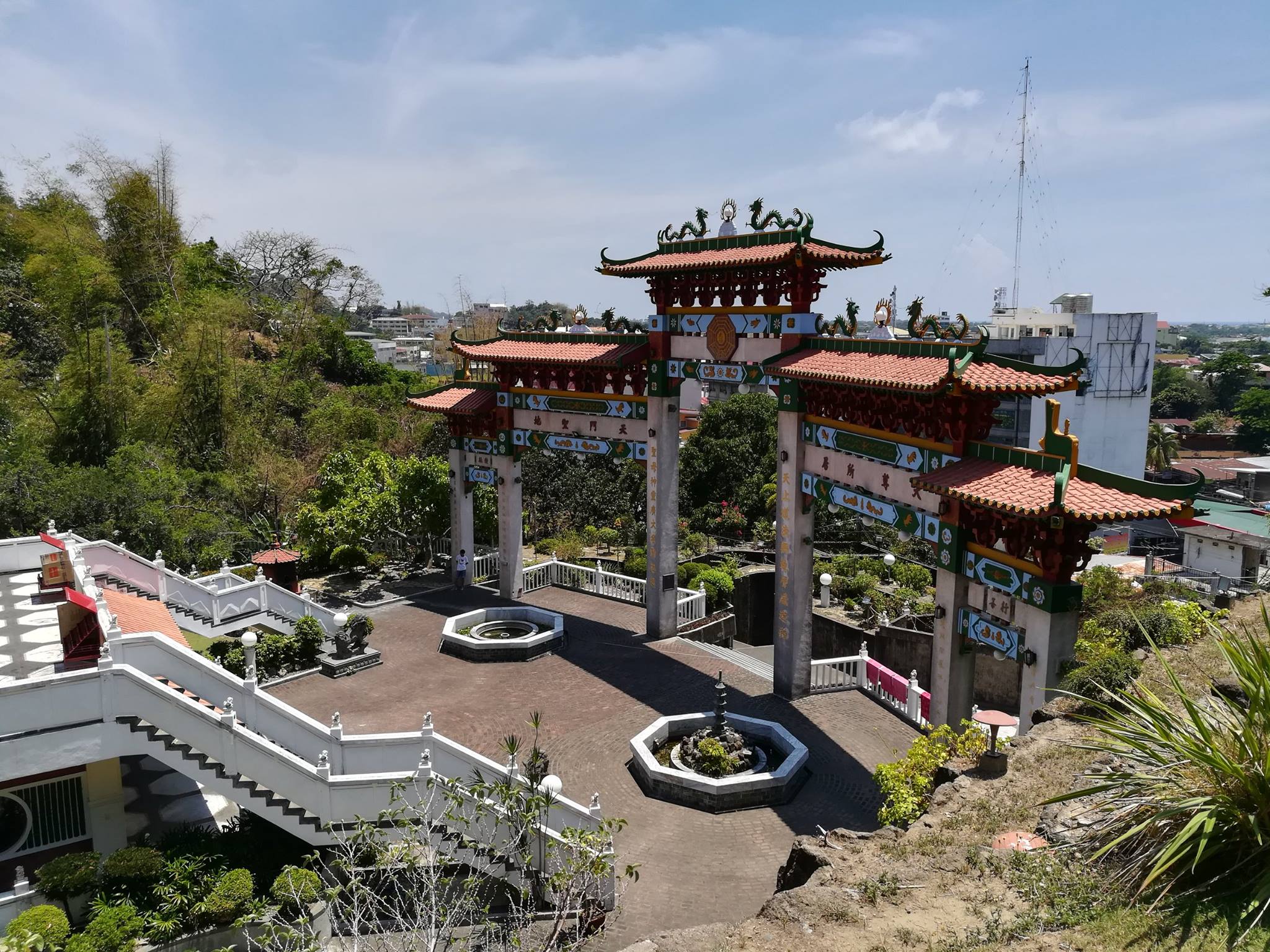 Ma-Cho Temple in San Fernando, La Union, featuring its ornate archway with dragon decorations, white staircases, and lush gardens under a clear sky.