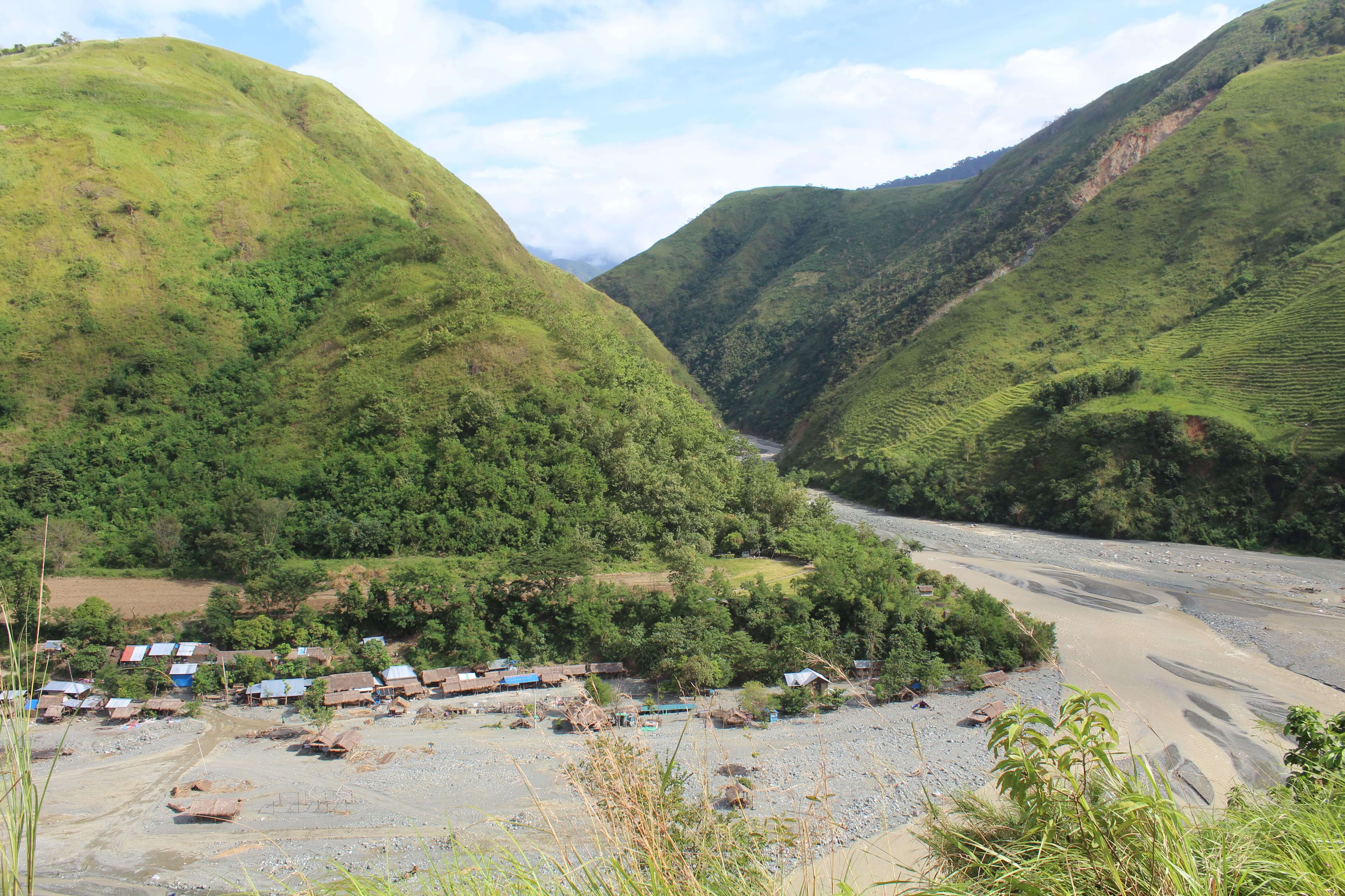 Mount Sawi valley with Dupinga River, village, and green hills under a partly cloudy sky