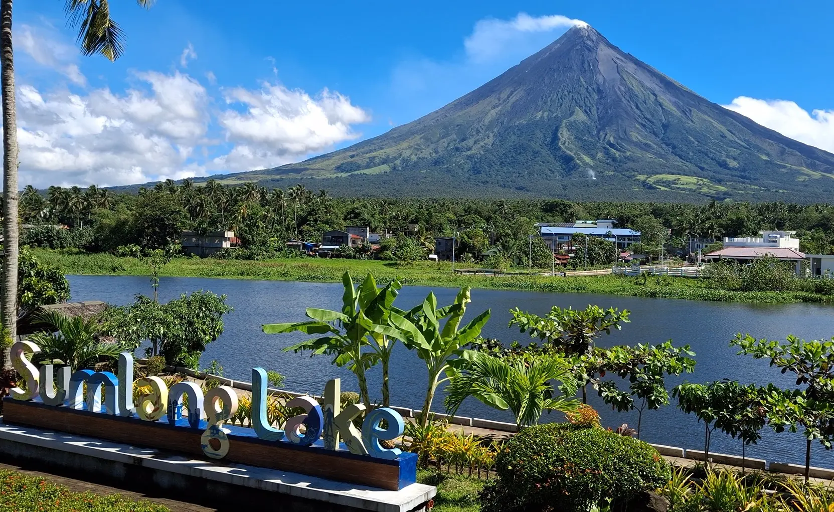 Scenic view of Mount Mayon reflecting on the calm waters of Sumlang Lake with a bamboo raft in the foreground