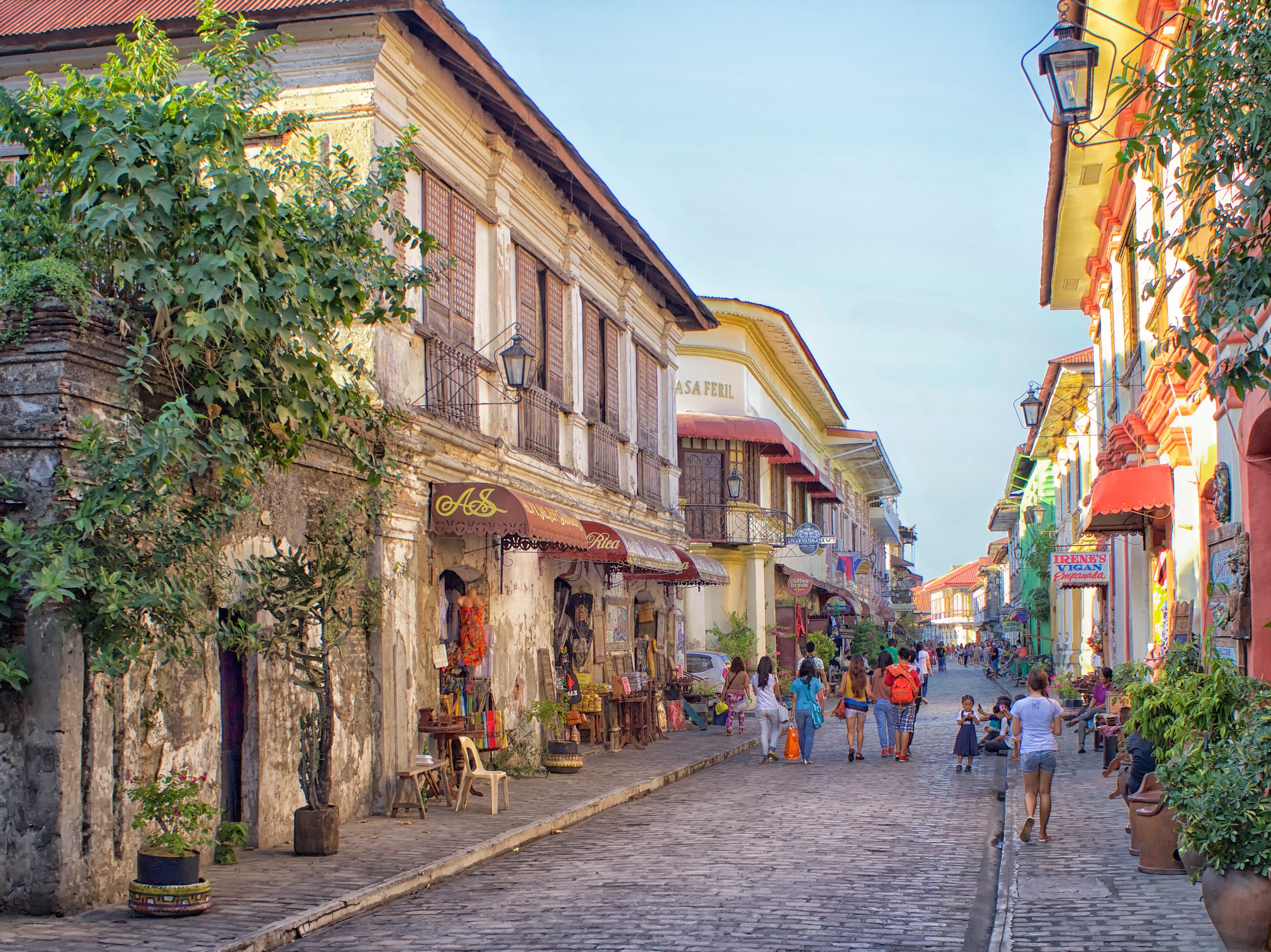 Historic cobblestone street in Vigan, Philippines, showcasing Spanish colonial architecture under a cloudy sky.